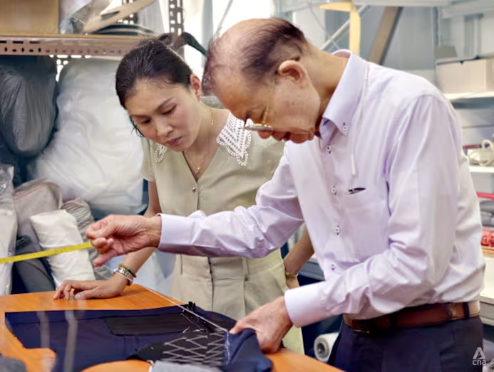 A man measuring a fabric and a woman watching the man